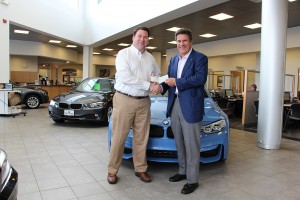 CBRE/NE vice president Michael Tamposi  makes donation to Vince Tulley, of Tulley’s Automotive Group.